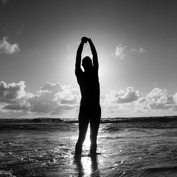 Silhouette of a man stretching at sunrise, symbolizing energy and well-being.